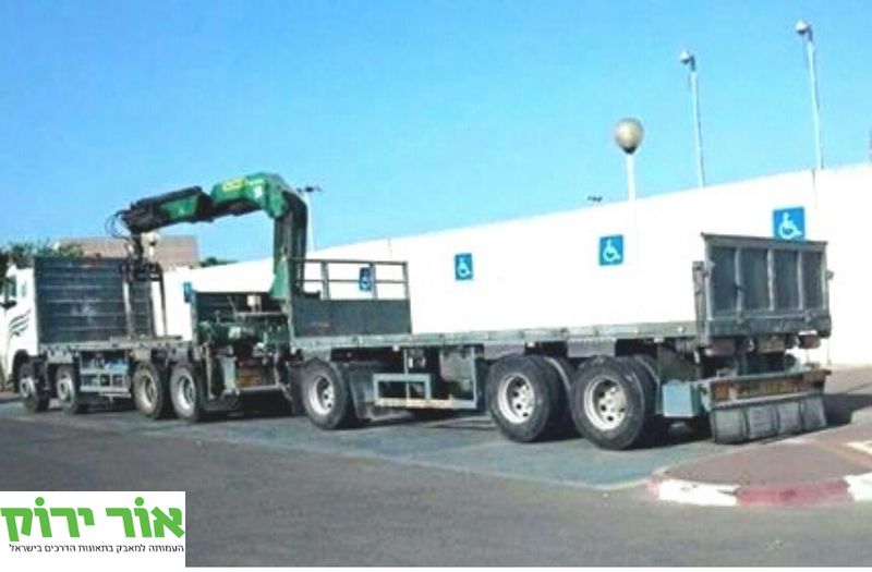 משאית חונה על פני מספר חניות נכים. אור ירוק